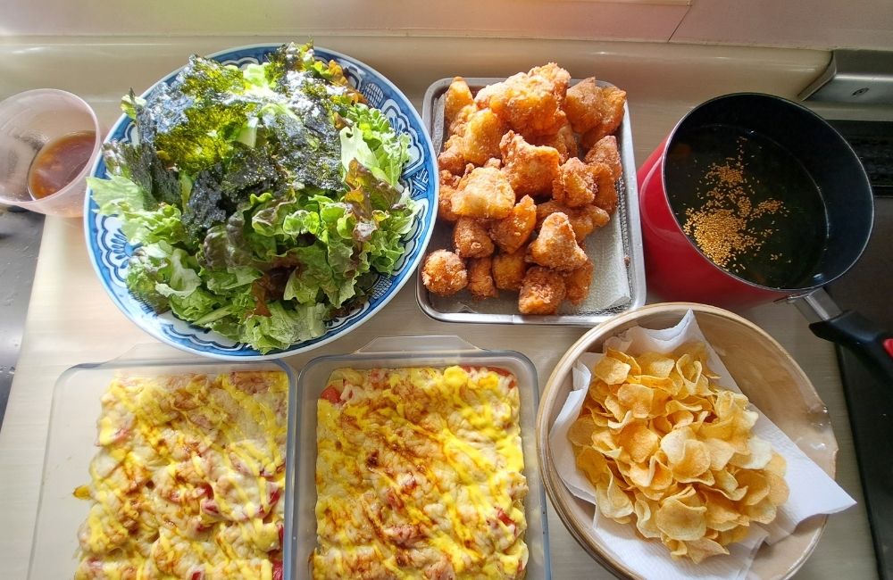 サラダ、揚げ物、保存容器に入った料理が並ぶMOANAの献立紹介
