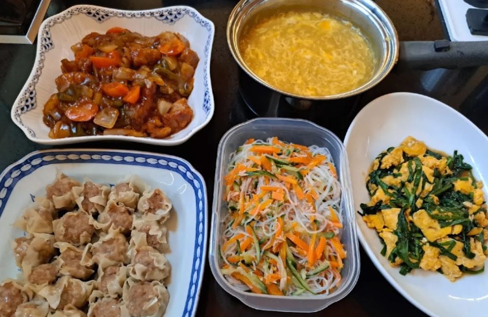 主菜、しゅうまい、野菜の副菜、汁物を並べたMOANAの料理紹介